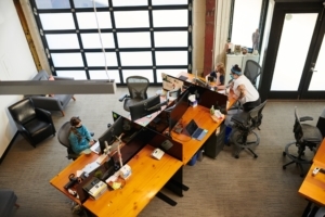 Several children sit work around a communal table in an office