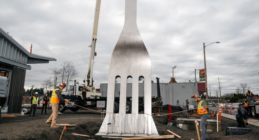 Solid Form employees installing giant metal fabricated fork outside a community culinary pod