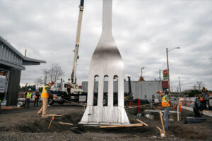 Solid Form employees installing giant metal fabricated fork outside a community culinary pod