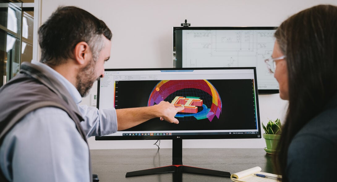 Two Systems West team members reviewing work on a computer screen