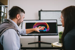 Two Systems West team members reviewing work on a computer screen