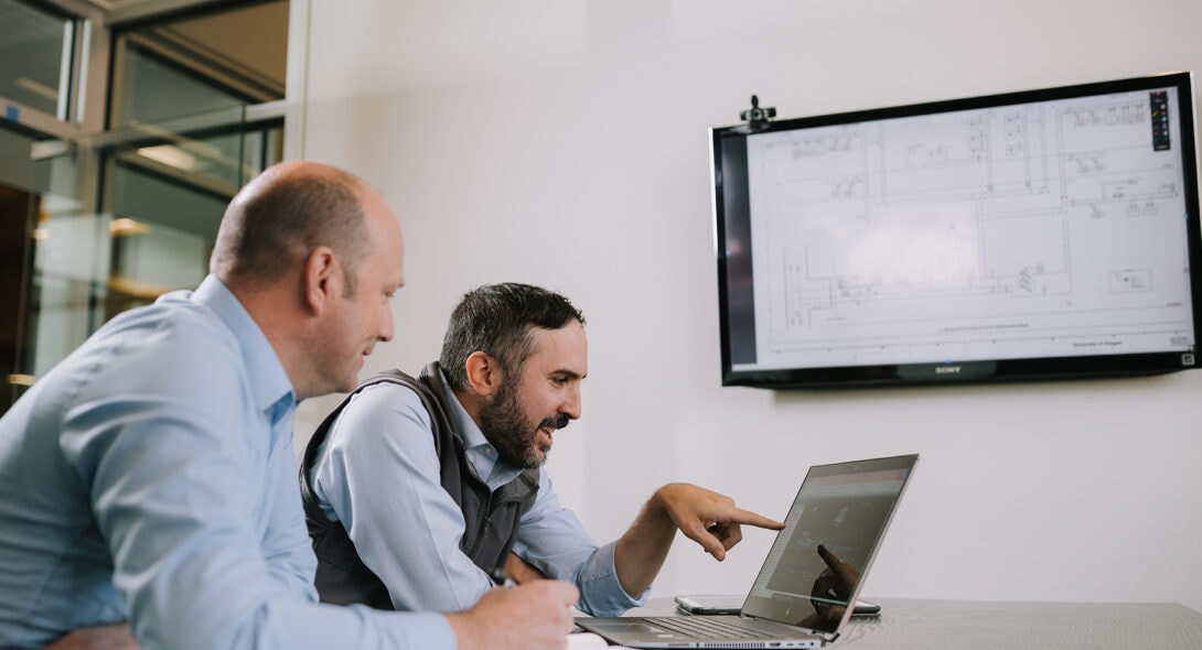 Two Systems West employees collaborating on a laptop