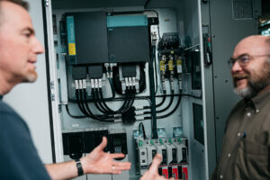 Team members discussing an open electrical panel